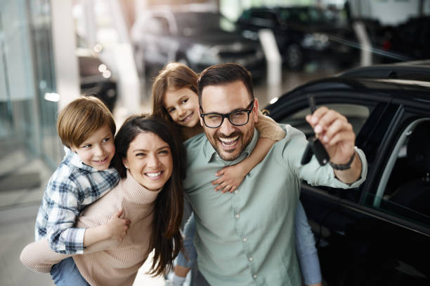 Family smiling next to their new car while holding insurance papers